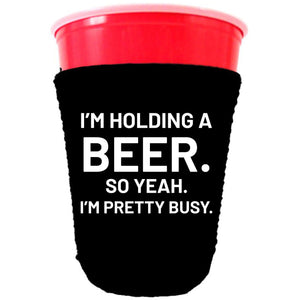 collapsible, neoprene solo cup koozie with "I'm holding a beer.." graphic printed on one side.