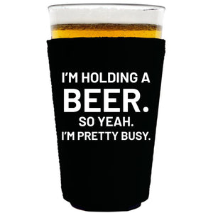 collapsible, neoprene 16oz. pint glass koozie with "I'm holding a beer.." graphic printed on one side.